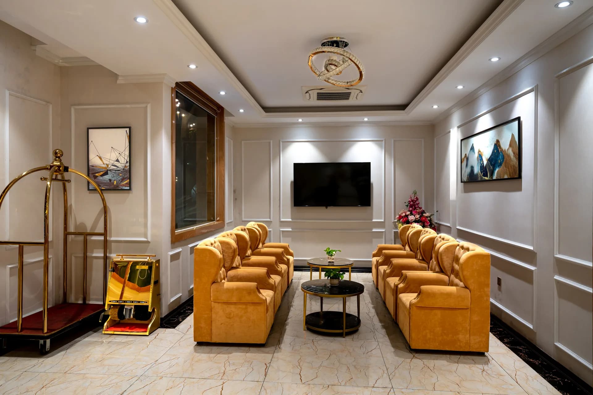 BookNoFees example image: Bright hotel lobby with gold-coloured armchairs and luggage trolleys