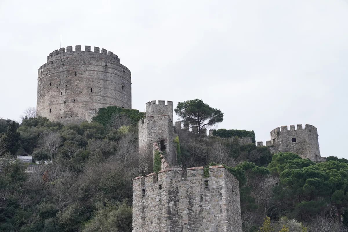 BookNoFees example image: A round stone tower with walls on a green hill