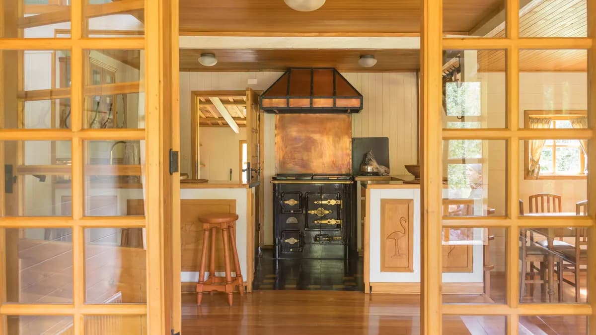 BookNoFees example image: Rustic kitchen with wooden fronts and seating behind a glass partition