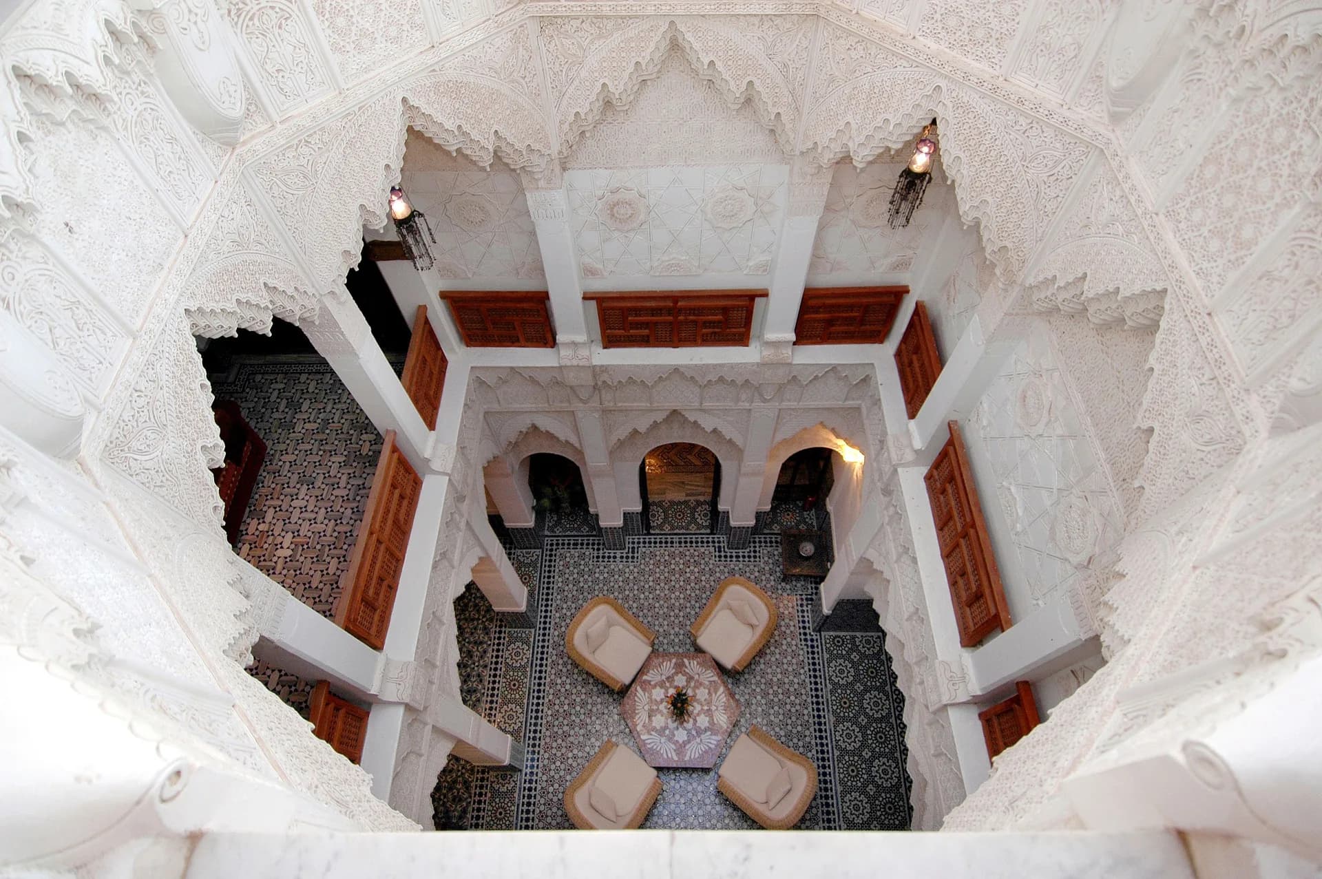 BookNoFees example image: A view from above into a riad courtyard with ornate arches and seating areas
