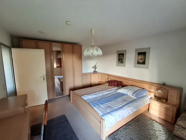 BookNoFees holiday home in Gailingen, Baden-Württemberg, Germany – Bedroom with double bed, wooden wardrobe with mirror, and bedside tables