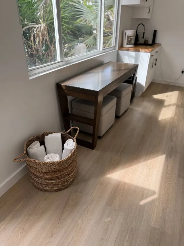BookNoFees holiday home in Cutler Bay, United States – Kitchen corner with wooden table, woven basket of towels, and window overlooking palms
