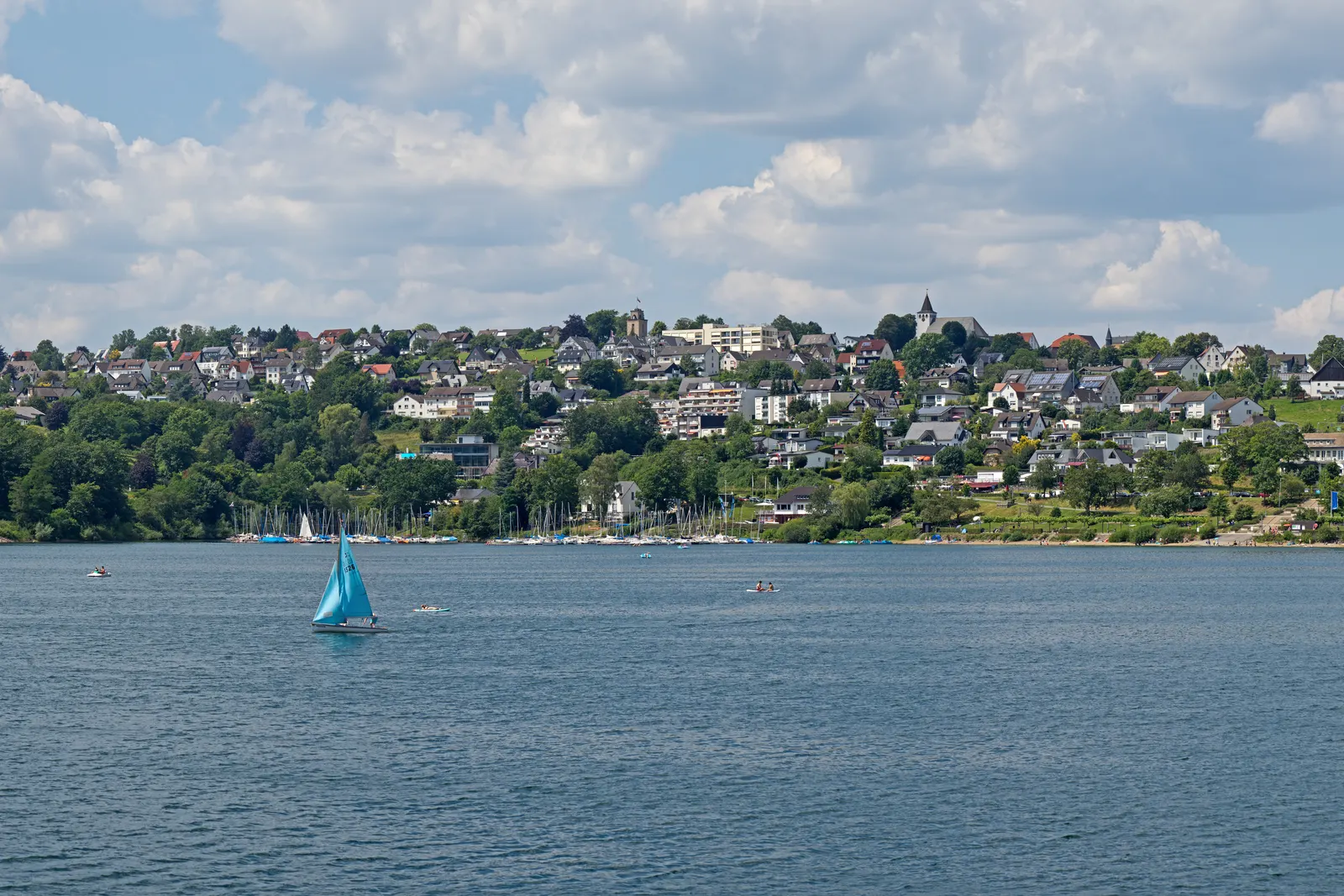 BookNoFees, Langscheid on the Sorpesee near Sundern: the lakeside village above the water, with a sailing boat in front, Sundern (Sauerland), Germany