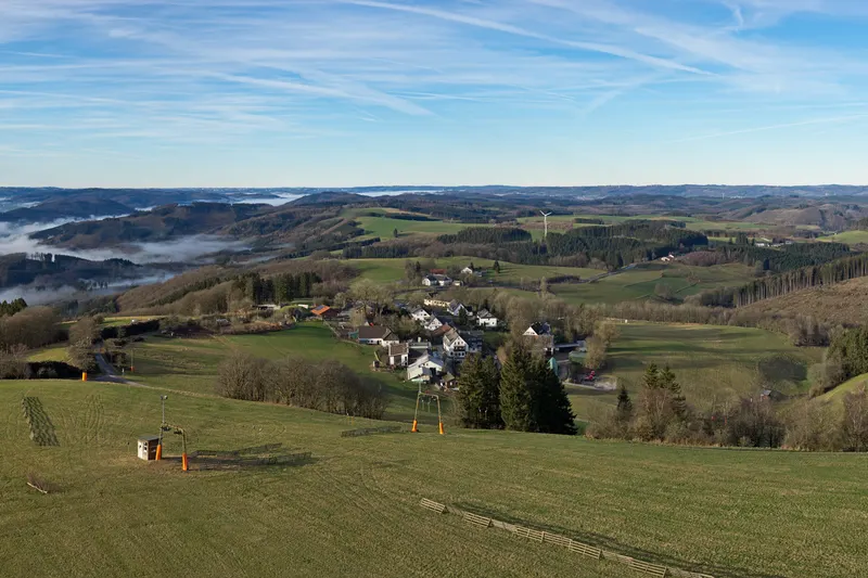 Wildewiese in the Sauerland hills, with a ski lift on the meadow and the village below