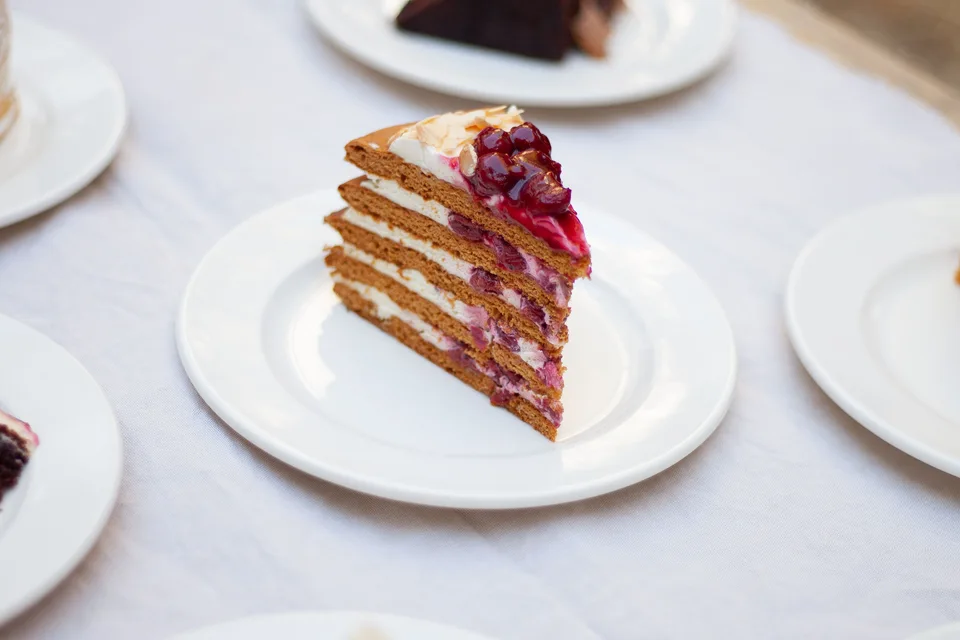 BookNoFees: Example photo: A slice of layered cake topped with berries on a white plate